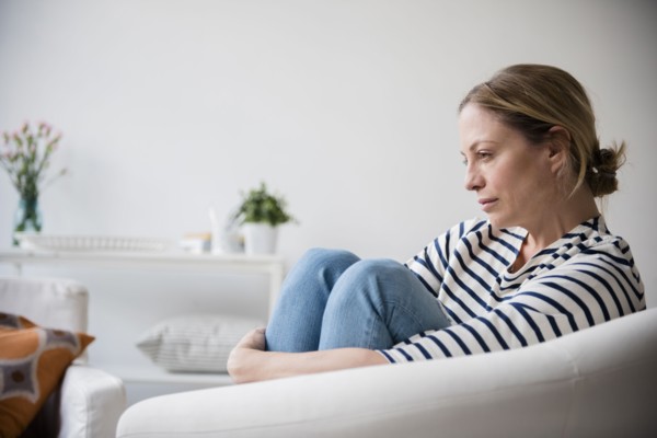 Caucasian woman sitting in armchair holding legs