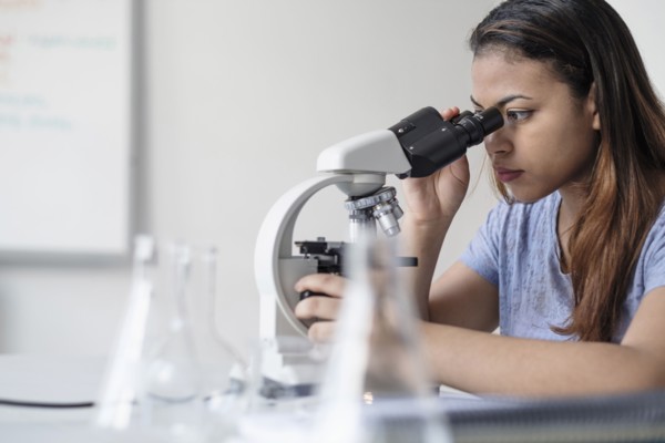Hispanic woman using microscope