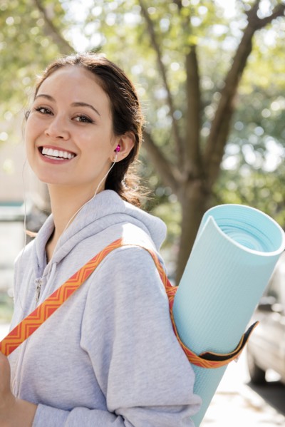 Thai woman posing in city carrying exercise mat