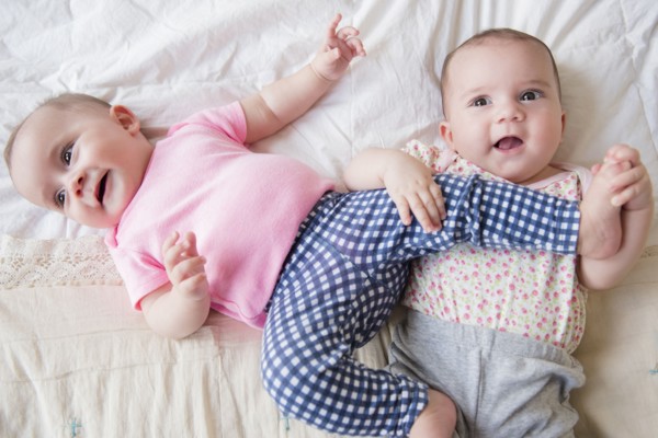 Caucasian twin baby girls playing on bed