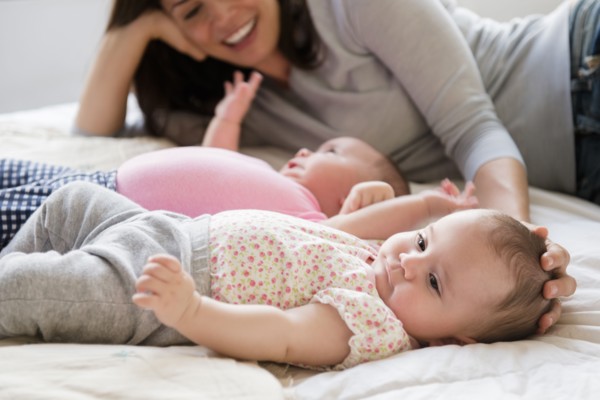Caucasian mother caressing head of baby daughter on bed