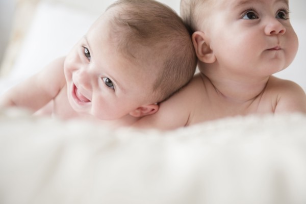 Caucasian twin baby girls laying on bed