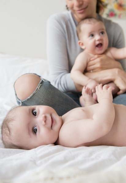 Caucasian mother with twin baby daughters on bed