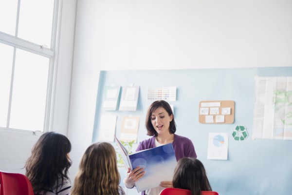 Teacher reading book to girls in classroom