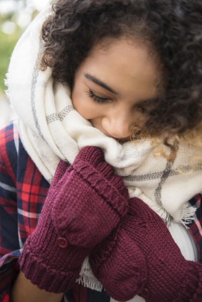 Mixed Race woman covering face with scarf