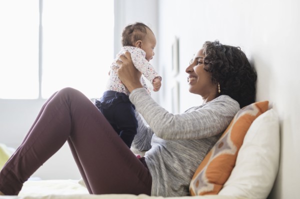Hispanic mother playing with baby daughter on bed