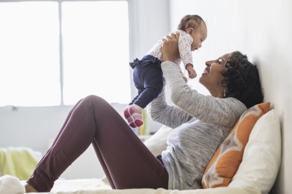 Hispanic mother playing with baby daughter on bed