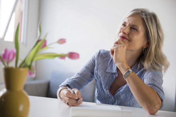 Pensive Caucasian woman writing on notepad