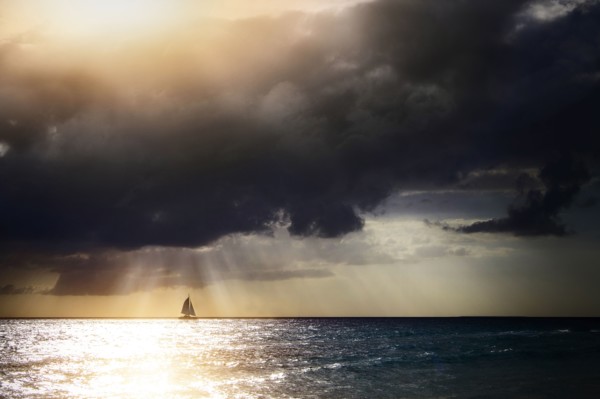 Sunbeams through storm clouds over sailboat