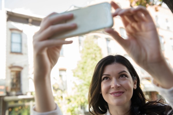Smiling Caucasian woman posing for cell phone selfie