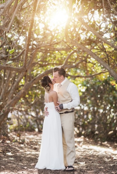 Caucasian bride and groom kissing under trees