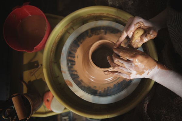 Hands of Caucasian woman shaping pottery clay on wheel