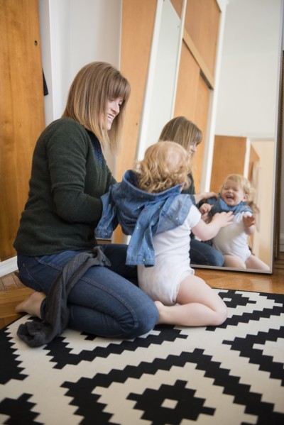 Reflection in mirror of Caucasian mother and daughter kneeling on floor