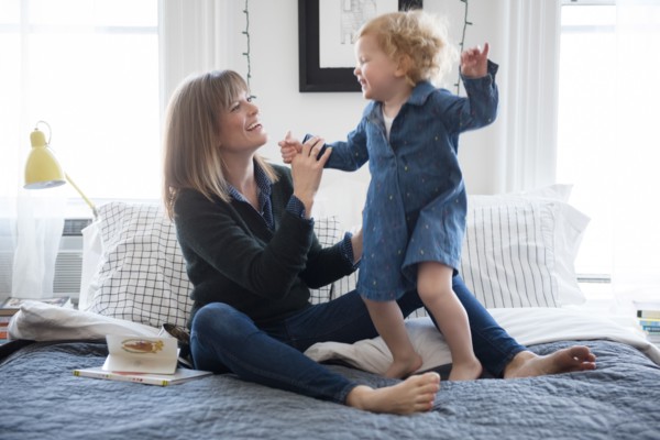 Caucasian mother sitting on bed playing with daughter