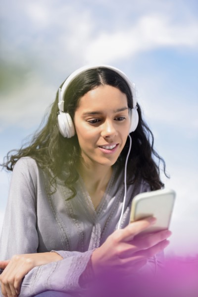 Hispanic woman listening to cell phone with headphones