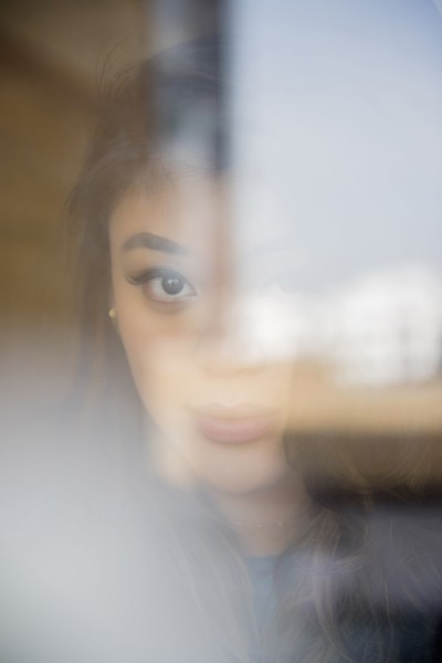 Face of serious Mixed Race woman behind window
