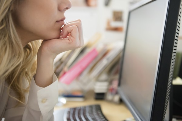 Caucasian woman with hand on chin reading computer