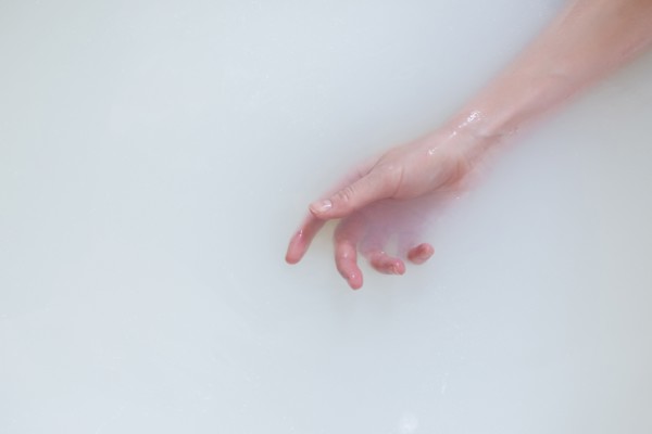 Hand of Caucasian woman in the milk bath