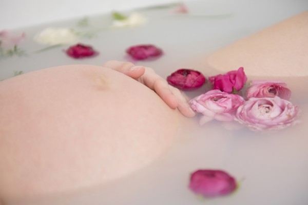 Caucasian expectant mother in milk bath with flowers