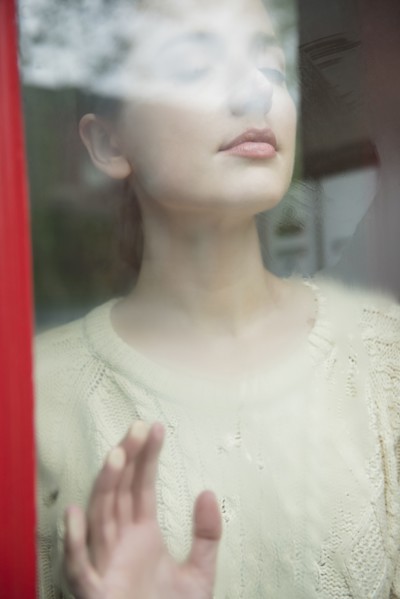 Caucasian woman daydreaming behind foggy window