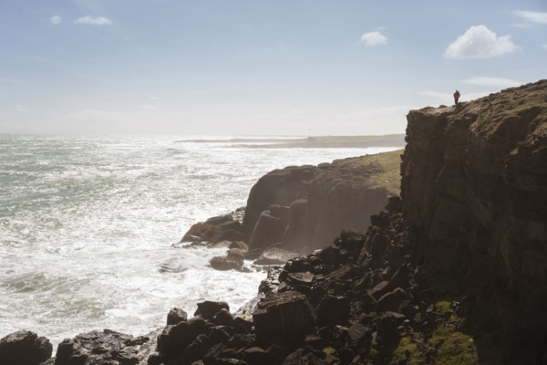 Chinese man standing on cliff at ocean