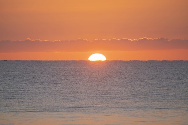 Sun rising above calm sea