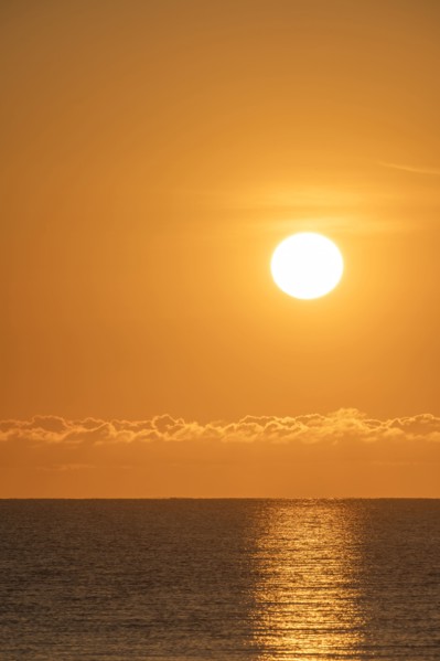 Blazing sunrise in orange sky over ocean