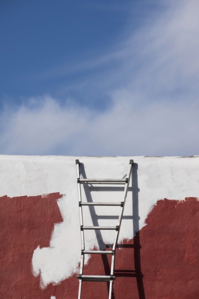 Ladder against partially painted brown and white wall