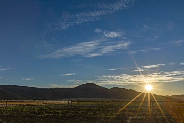 Sun rising over fields and hills