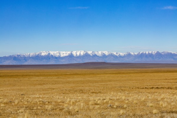 Desert and distant mountains under blue sky