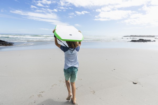 Boy with surfboard on beach