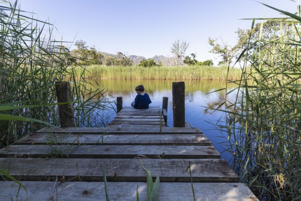 Boy sitting on wooden pier