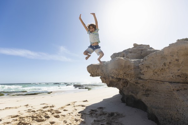 Boy jumping off rock
