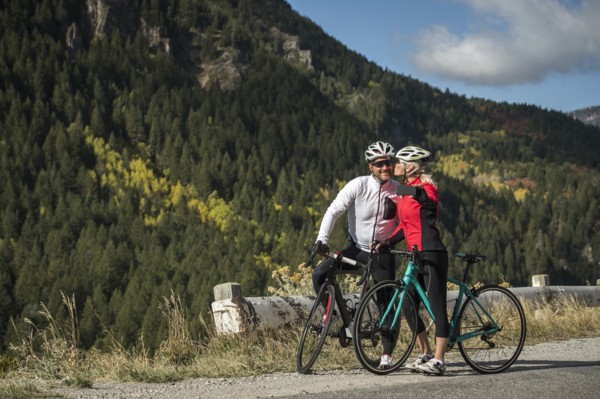 Smiling couple with bicycles taking selfie in mountain landscape