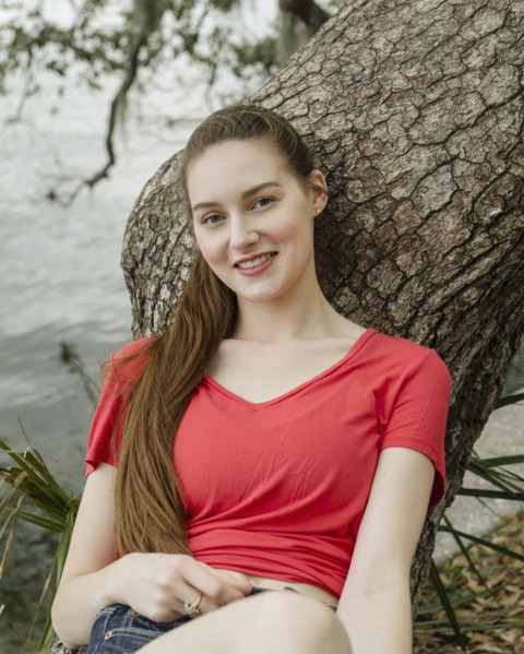 Portrait of smiling woman leaning against tree trunk