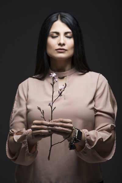 Studio portrait of woman holding blooming twig with eyes closed