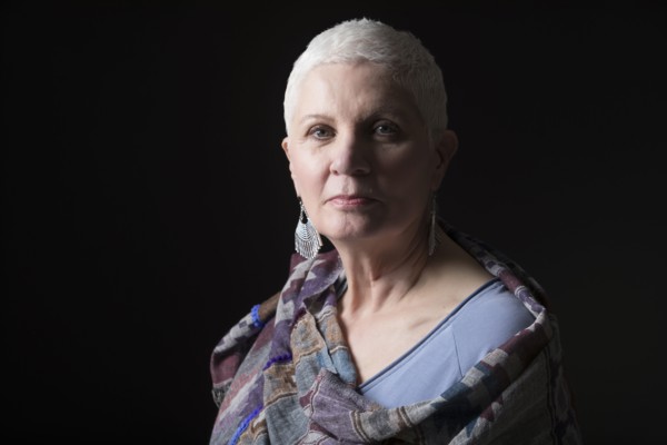 Studio portrait of woman with white short hair wrapped in shawl