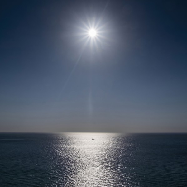 Sun shining above calm ocean surface