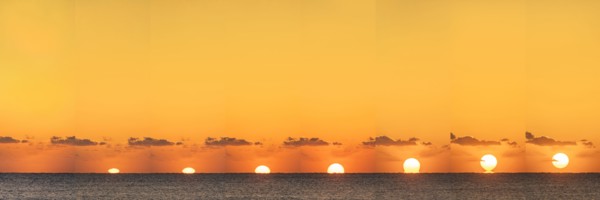 Sequential sun rising above calm ocean