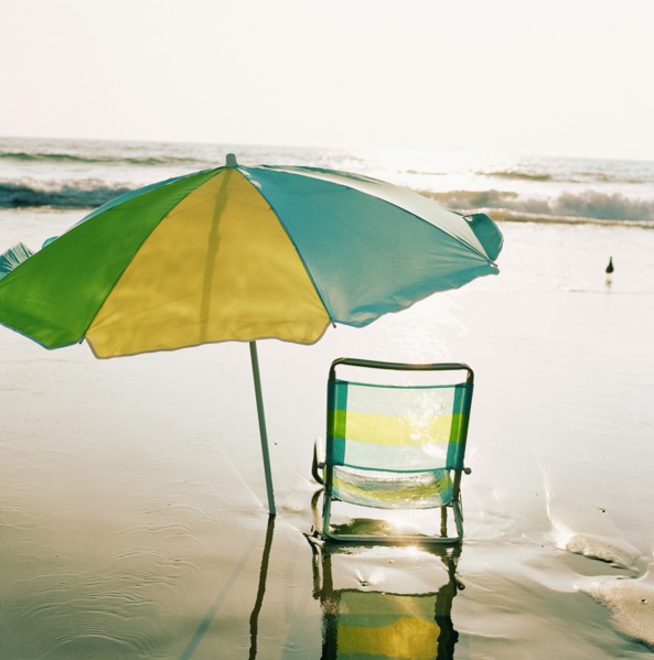 Beach chair and umbrella on beach at sunset