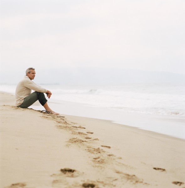 Man sitting on beach looking at ocean