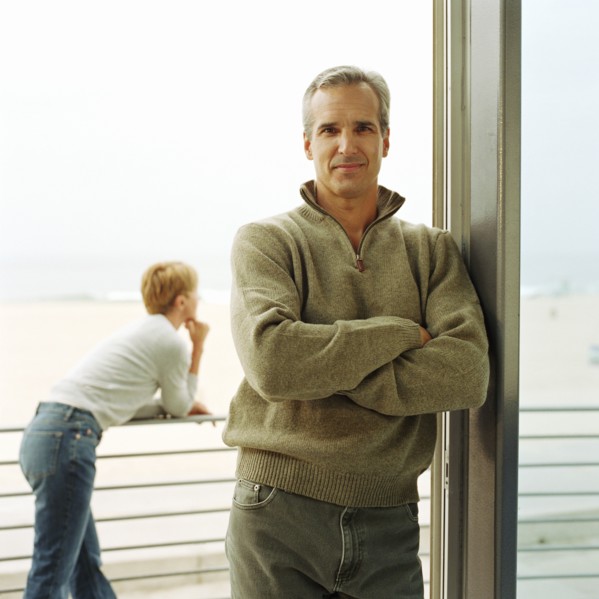 Portrait of man leaning on doorway of house
