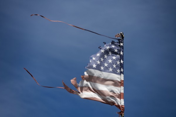 Worn and wind-torn American flag blowing against blue sky