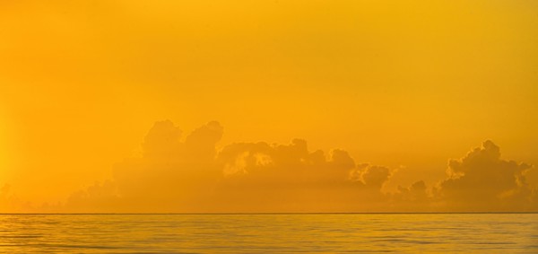Golden sunrise clouds over calm ocean