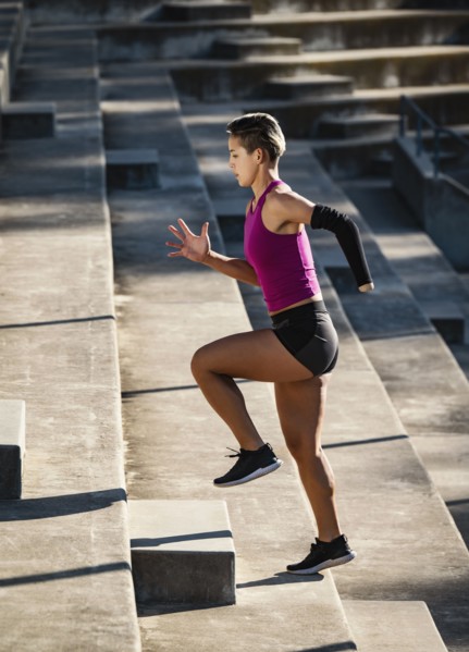 Woman with amputated hand jogging up steps