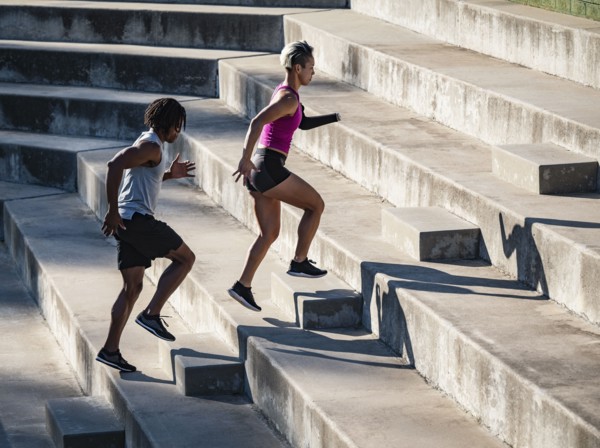 Athletic man and woman with amputated hand running up steps