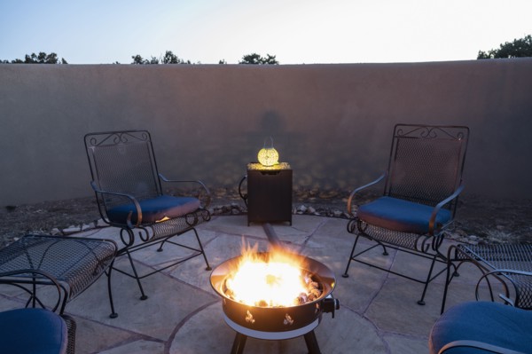Chairs around back yard fire pit at dusk