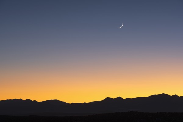 Jemez Mountains at dusk with crescent moon on sky