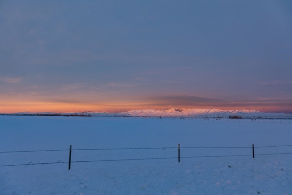 USA, Idaho, Bellevue, Snow covered field with hills in distance at sunrise