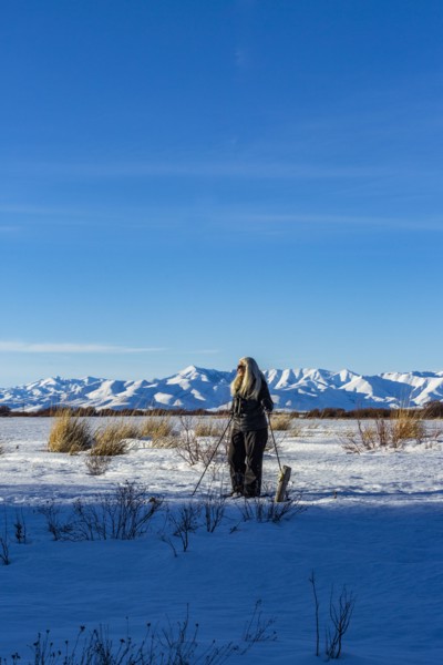 Senior blonde woman snow shoeing in snow covered landscape
